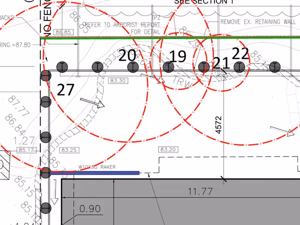 Tree protection zones and fence posts beside an excavation shoring section